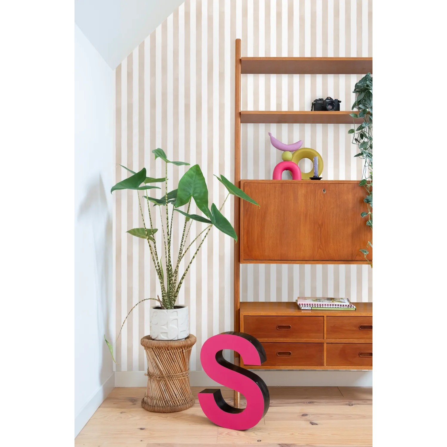 ESTAhome Vliestapete mit beigen und weißen Streifen an einer Wand, daneben Pflanze und Holzregal.