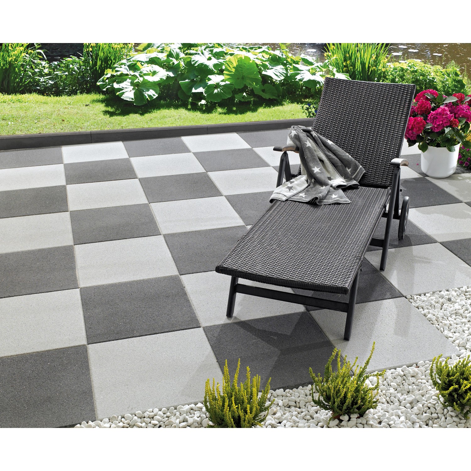 Verlegte, silbergraue Terrassenplatten Almelo 50x50 cm im Schachbrettmuster mit Liege.