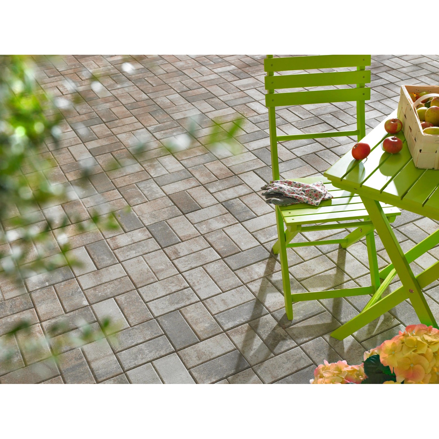 Verlegte Rechteck-Pflastersteine Jura-Nuanciert (20x10x6 cm) auf Terrasse mit Gartenmöbeln.