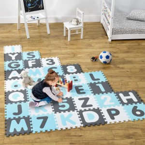 Kind spielt auf Juskys Puzzlematte Noah mit Buchstaben und Zahlen in blau, grau und weiß.