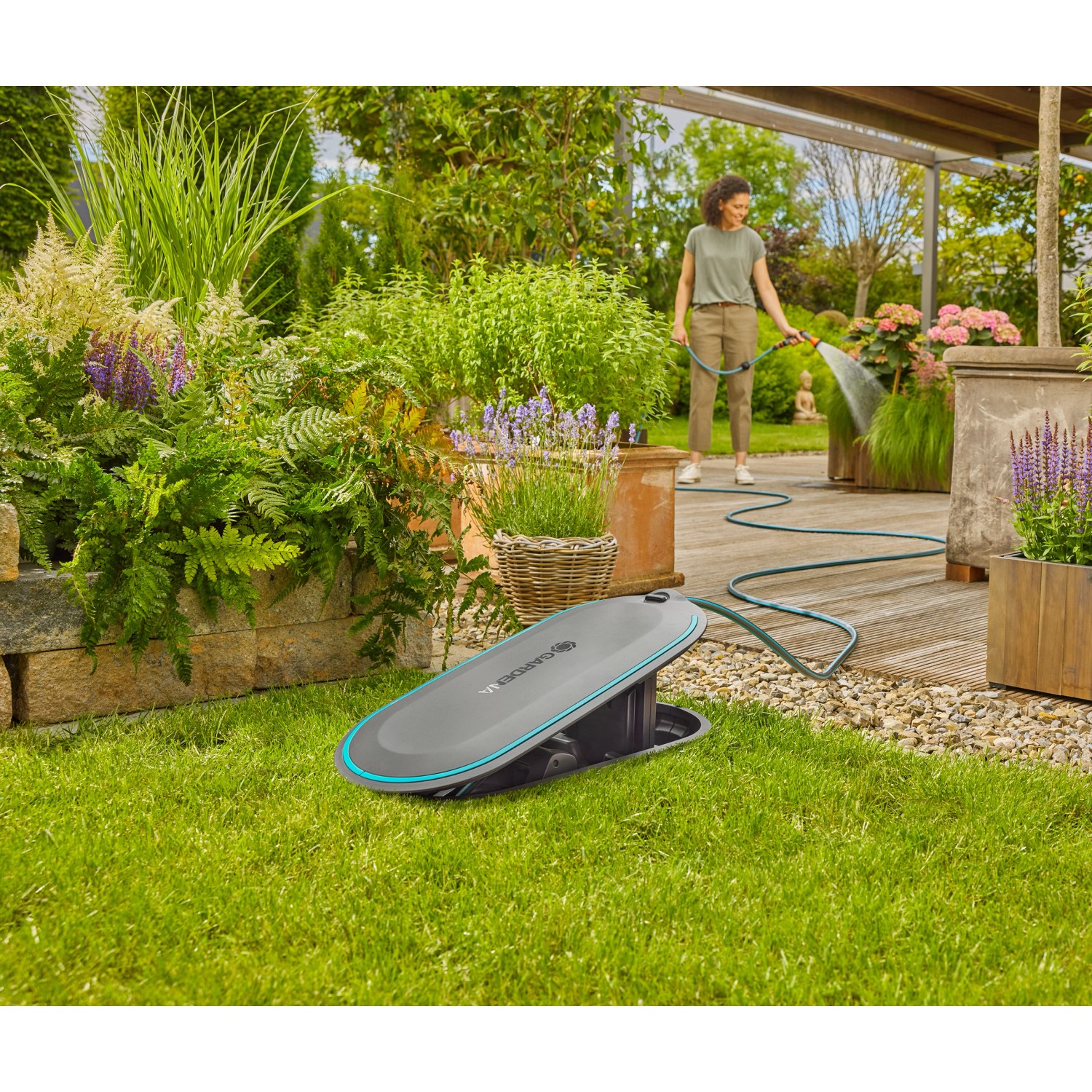 Gardena Undercover Schlauchbox RollUp M im Garten, Frau bewässert Pflanzen.