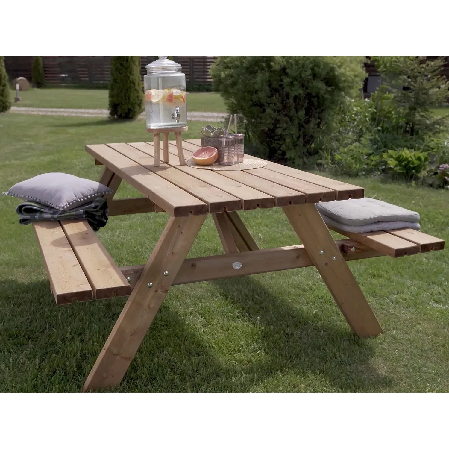 Axi Picknicktisch Julie aus Holz, braun, 177x154cm, mit Getränkespender und Kissen im Garten.