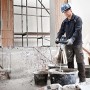 Handwerker mit Bosch Professional Rührwerk GRW 12 E beim Anmischen von Mörtel auf einer Baustelle.