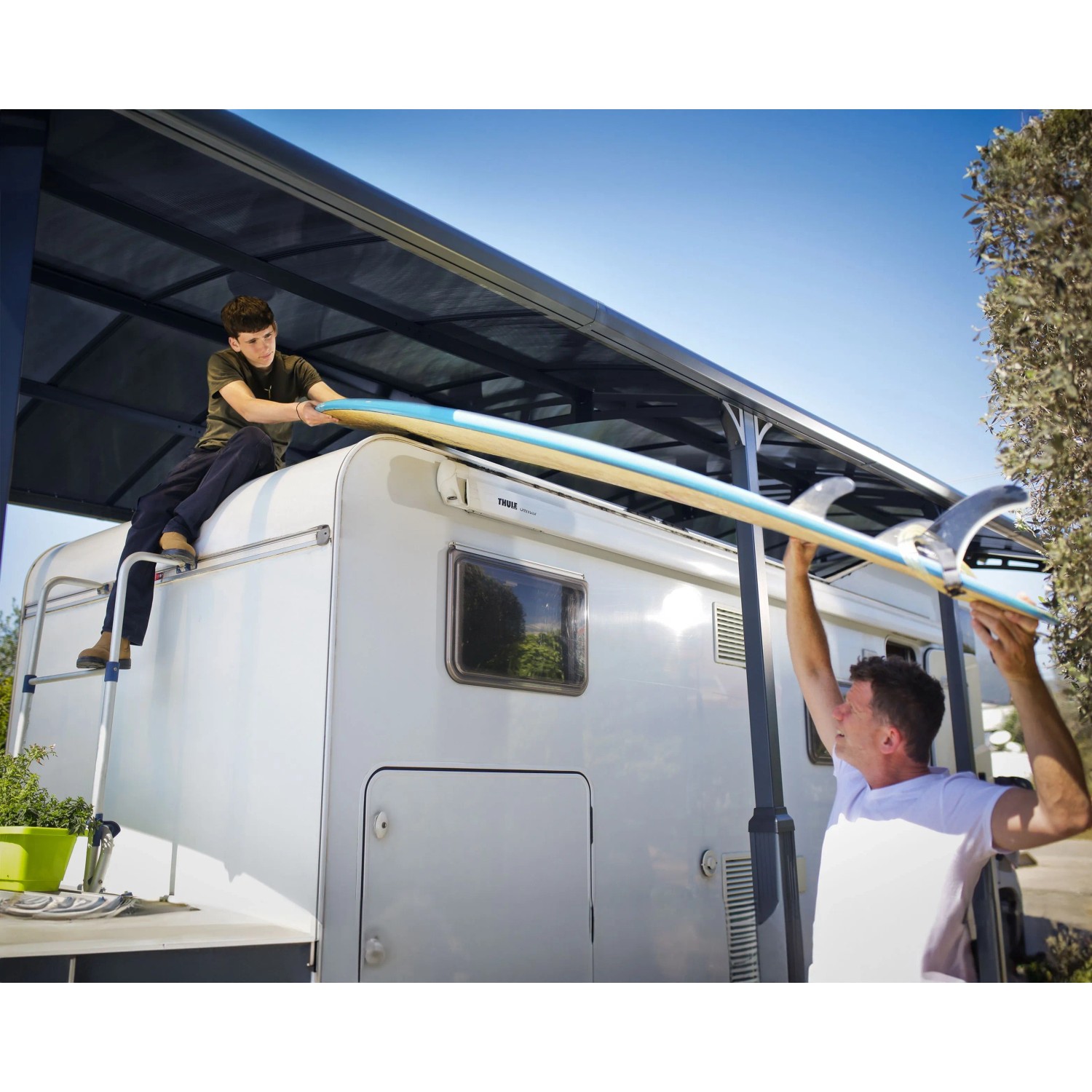Canopia Carport Arcadia Alpine 5000 Anthrazit mit montiertem Surfbrett auf Wohnwagen.