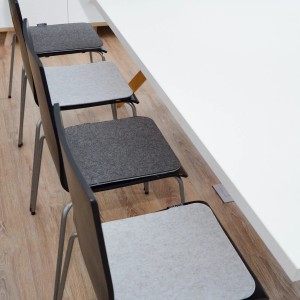 Eckige, hellgraue DuneDesign Filz Sitzkissen (35x35 cm) auf Stühlen.