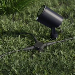 Schwarzes 24V Cross-Road-Verbindungsstück für Außenbeleuchtungssysteme, mit Kabeln und Leuchte im Garten. IP67.