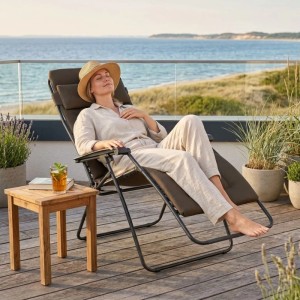 Frau entspannt im Lafuma Relax Liegestuhl RSX Clip XL Air Comfort Taupe Braun auf Holzterrasse mit Meerblick. Zero Gravity Position.