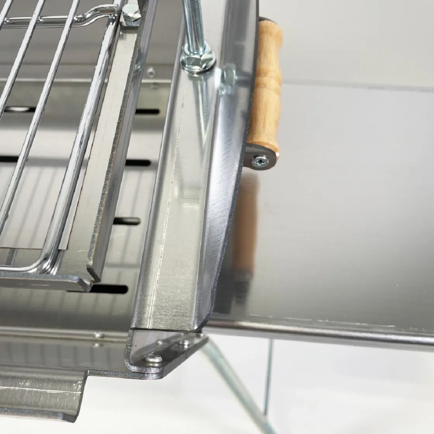 Detailaufnahme: Grillpeter Mangal Astana Edelstahl Grill mit Rost und Holzgriff.