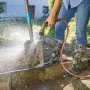 Gardena Comfort Reinigungsspritze ecoPulse™ im Einsatz zur Reinigung einer Schaufel im Garten.