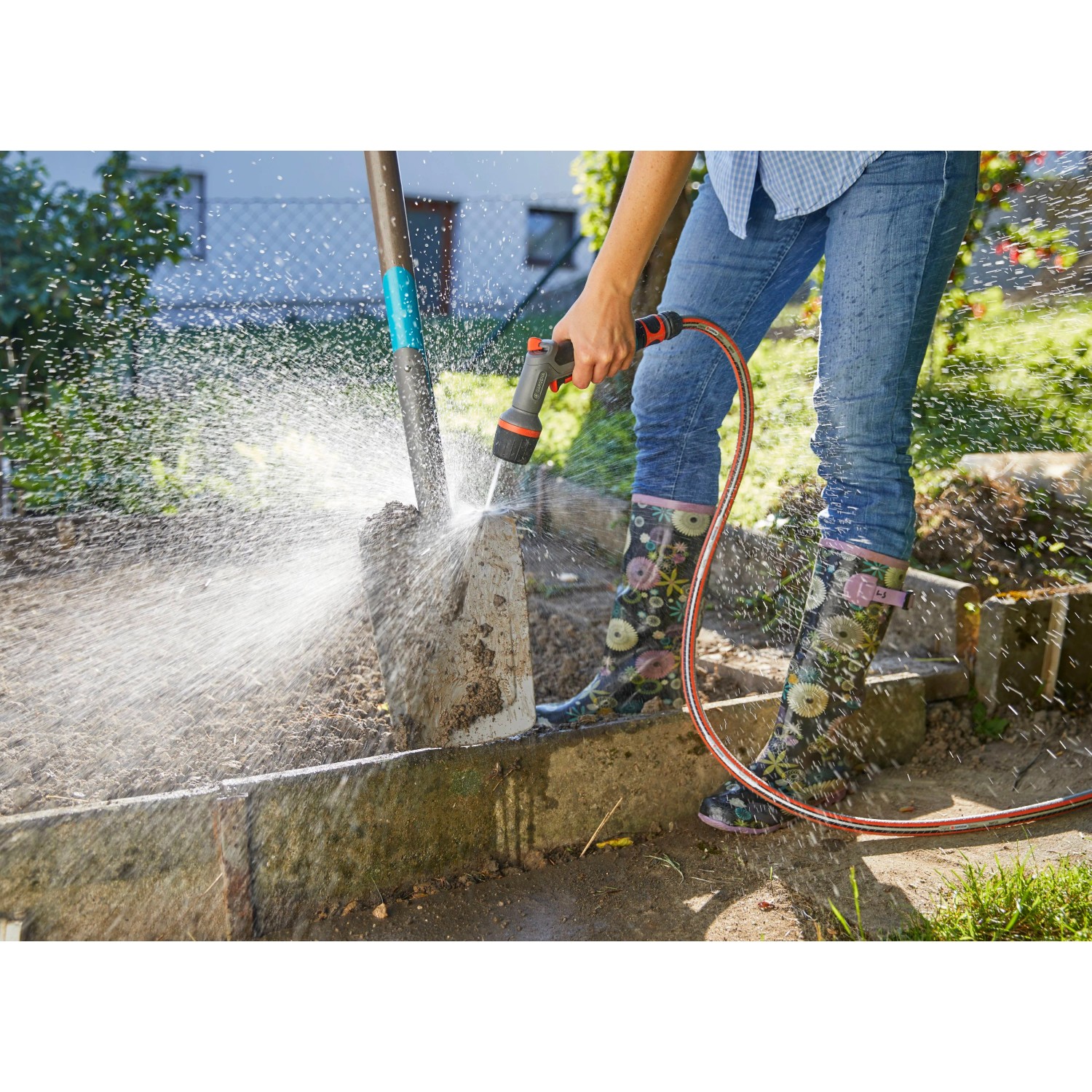 Gardena Comfort Reinigungsspritze ecoPulse™ im Einsatz zur Reinigung einer Schaufel im Garten.