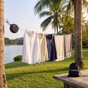 Schwarze Wiltec Ausziehwäscheleine 10m zwischen Palmen mit hängender Wäsche und Beutel. Ideal für Camping & Reise.