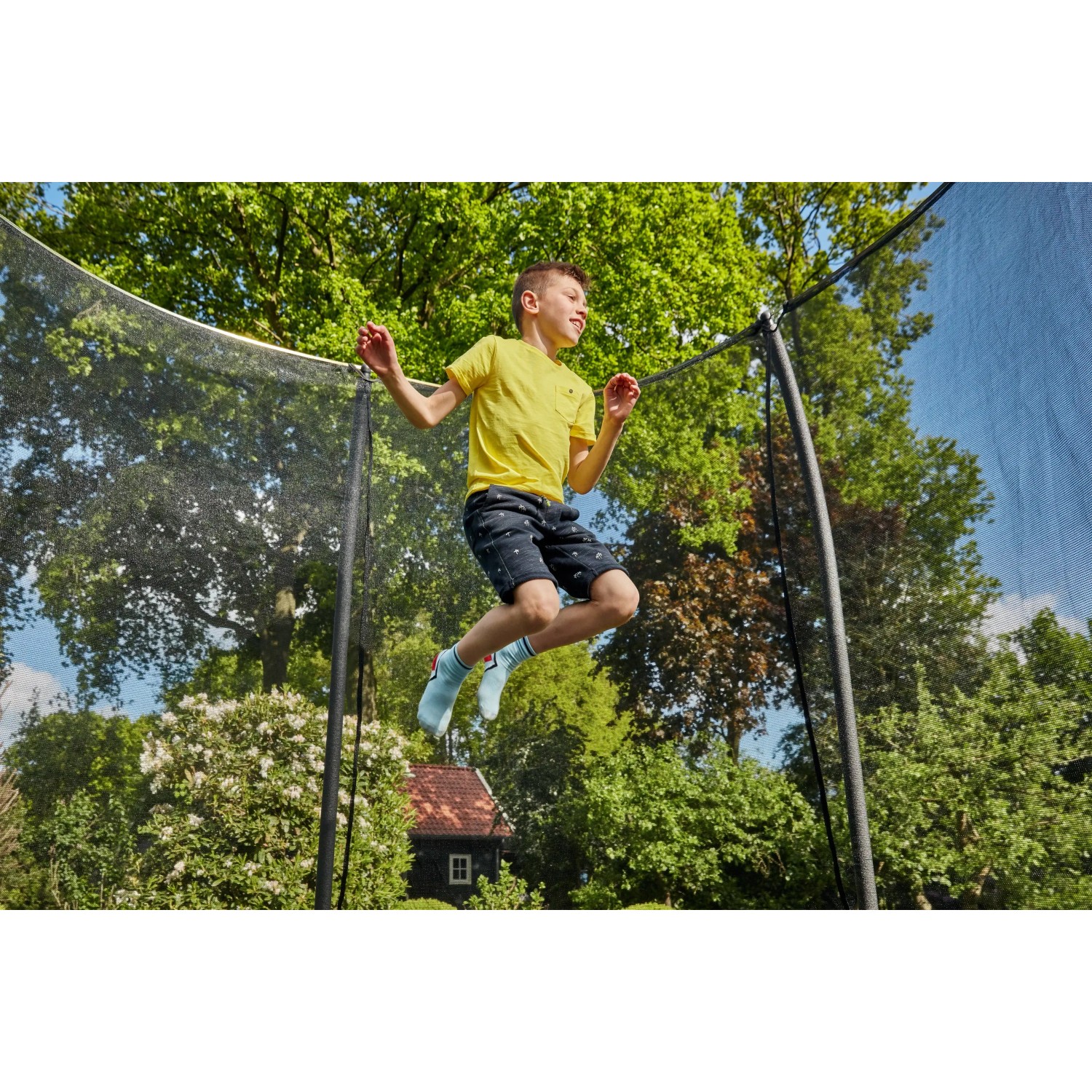 Junge springt auf grünem Salta Gartentrampolin Comfort Edition mit Sicherheitsnetz.