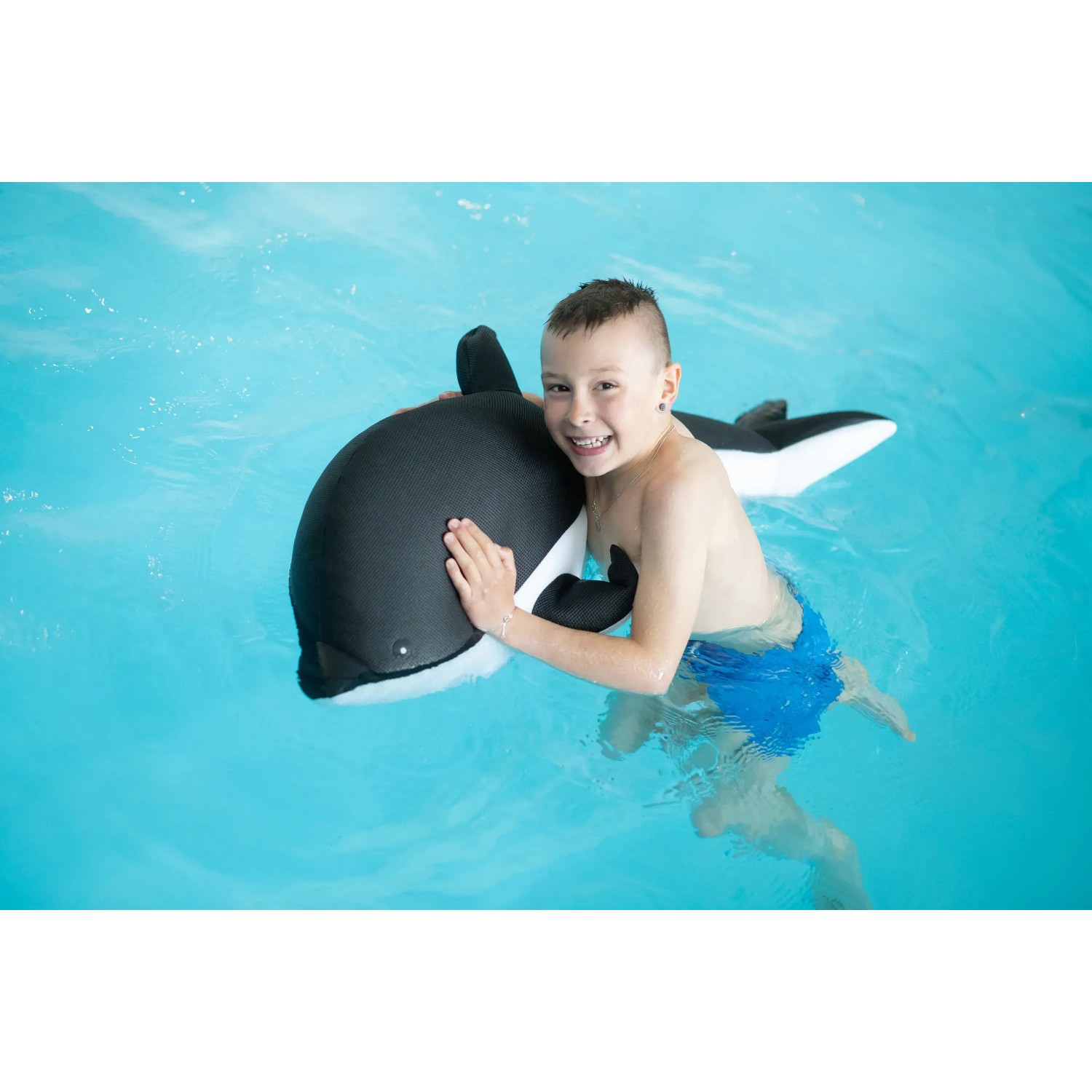 Junge schwimmt mit Westmann Pool Buddy Delfin grau-weiß im Pool. Wasserspielzeug für Kinder.