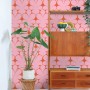 ESTAhome Vliestapete mit rosa-roten Retro-Ornamenten an einer Wand, daneben ein Holzregal und eine Zimmerpflanze.