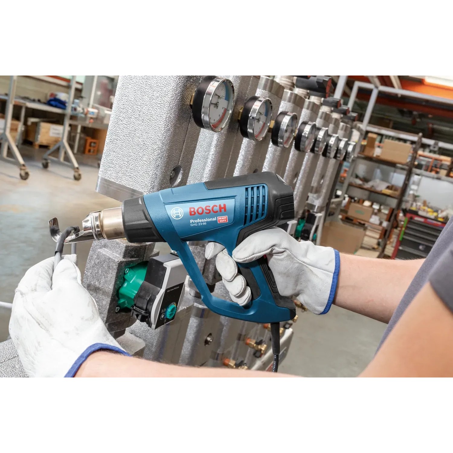 Bosch Professional GHG 23-66 Heißluftgebläse in Aktion, blau, mit Düsen und Koffer.
