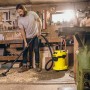 Mann saugt mit gelbem Kärcher WD 3 P Nass-Trockensauger Späne in Werkstatt.