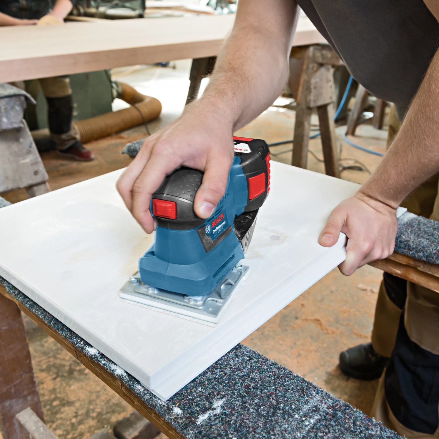 Bosch Professional GSS 18V-10 Akku-Schwingschleifer im Einsatz beim Schleifen einer weißen Oberfläche.