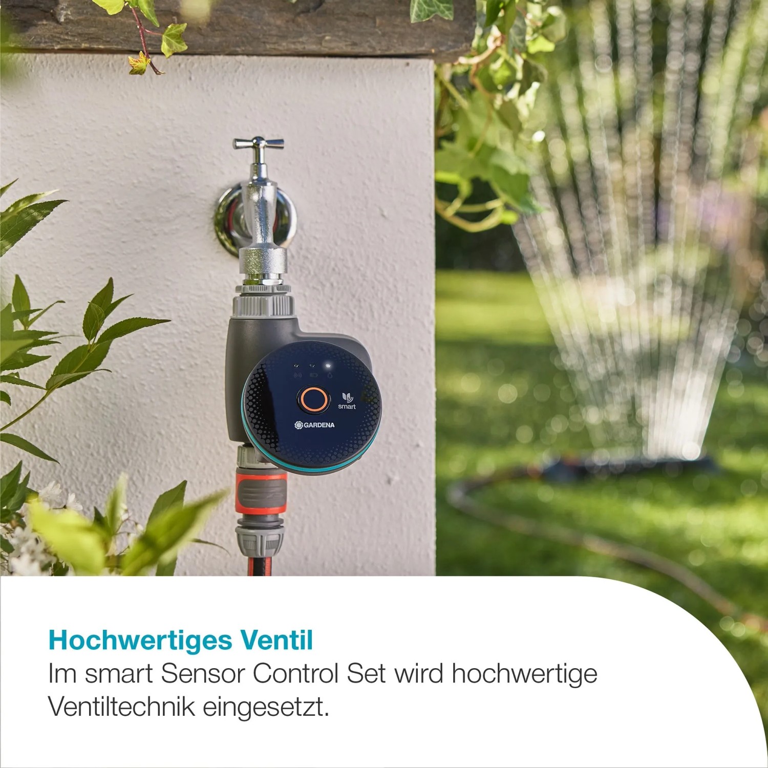 Gardena Smart Sensor Control Set am Wasserhahn mit Rasensprenger im Hintergrund.