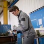 Mann schleift Metall mit Bosch Professional Winkelschleifer GWS 14-125 Solo, Funken sprühen.