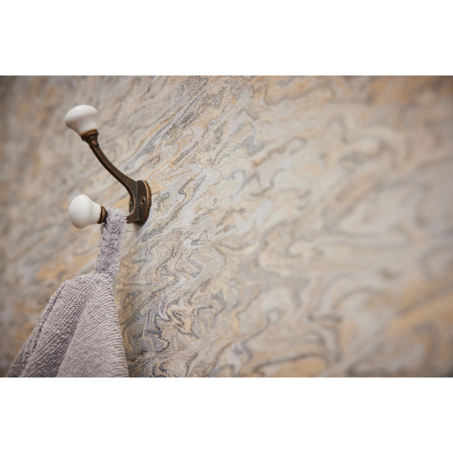 Vliestapete abstrakt hellorange/beige mit leichtem Glanz und Struktur an Wand mit Handtuch.