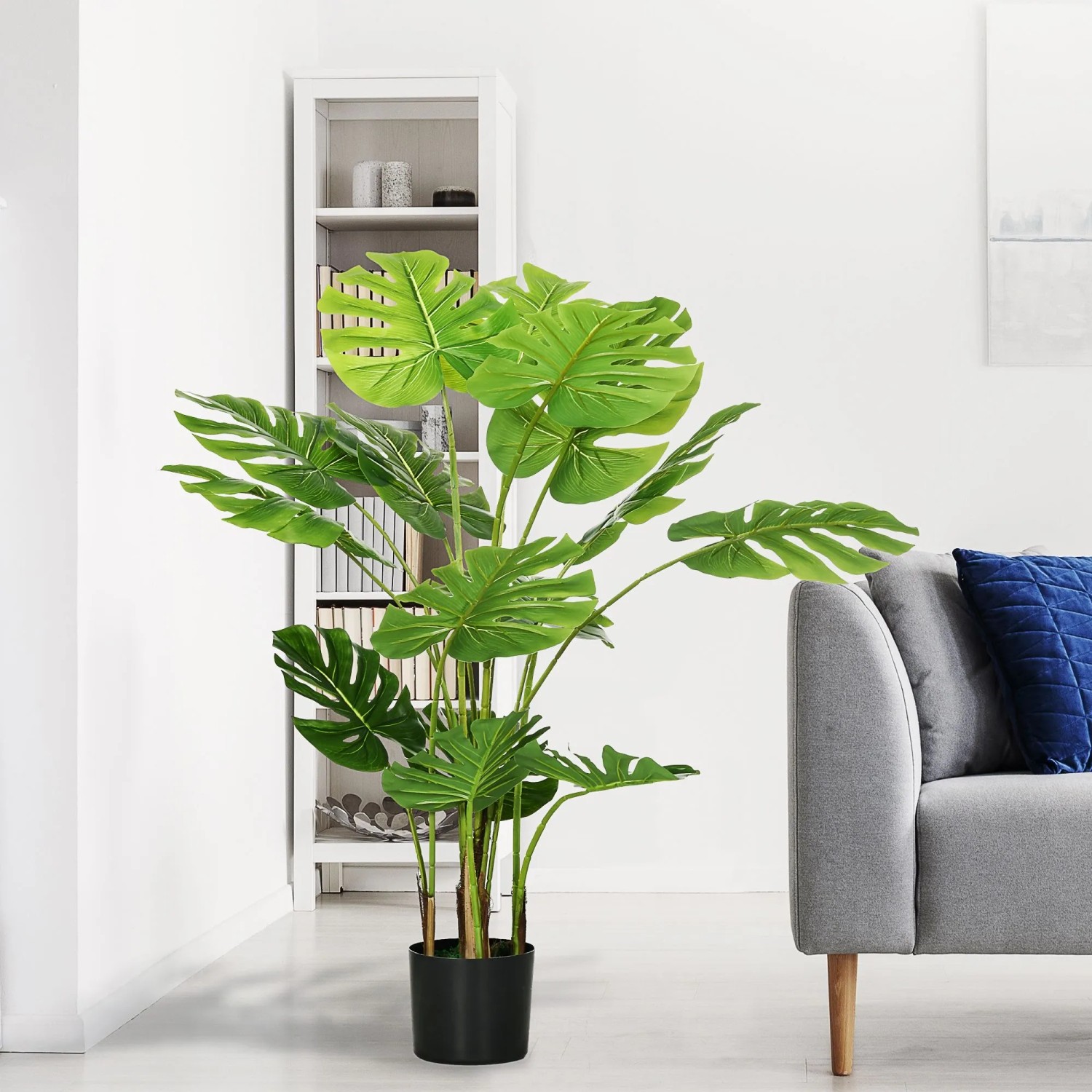 HOMCOM Künstliche Pflanze 120 cm mit großen grünen Blättern im schwarzen Übertopf, im Wohnzimmer neben Sofa.