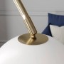 Nahaufnahme der Lindby Bogenleuchte Cynthia. Goldener Messingarm trifft auf weißen Glasschirm. Moderne Stehlampe.