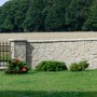 Stegu Verblender Jura Beige: Mauer aus Natursteinoptik im Außenbereich, umgeben von Grün.