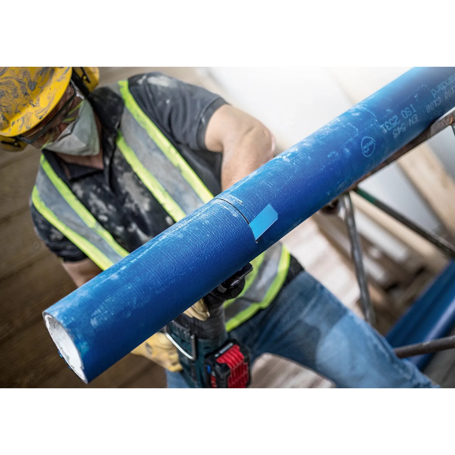 Bosch Expert Säbelsägeblatt S 1750 RD schneidet blaues Zementrohr, Arbeiter im Hintergrund.