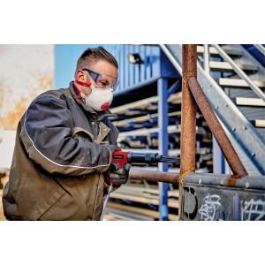 Einhell Nadelentroster-Aufsatz im Einsatz: Mann entfernt Rost von Metall mit Druckluft-Meißelhammer.