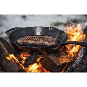 Petromax Grillpfanne aus Gusseisen (30cm) mit Steak über offenem Feuer. Grillutensil für Outdoor-Küche.