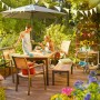Gartenszene mit Holz Stapelstuhl Bonlee und Gartentisch auf einer Terrasse.