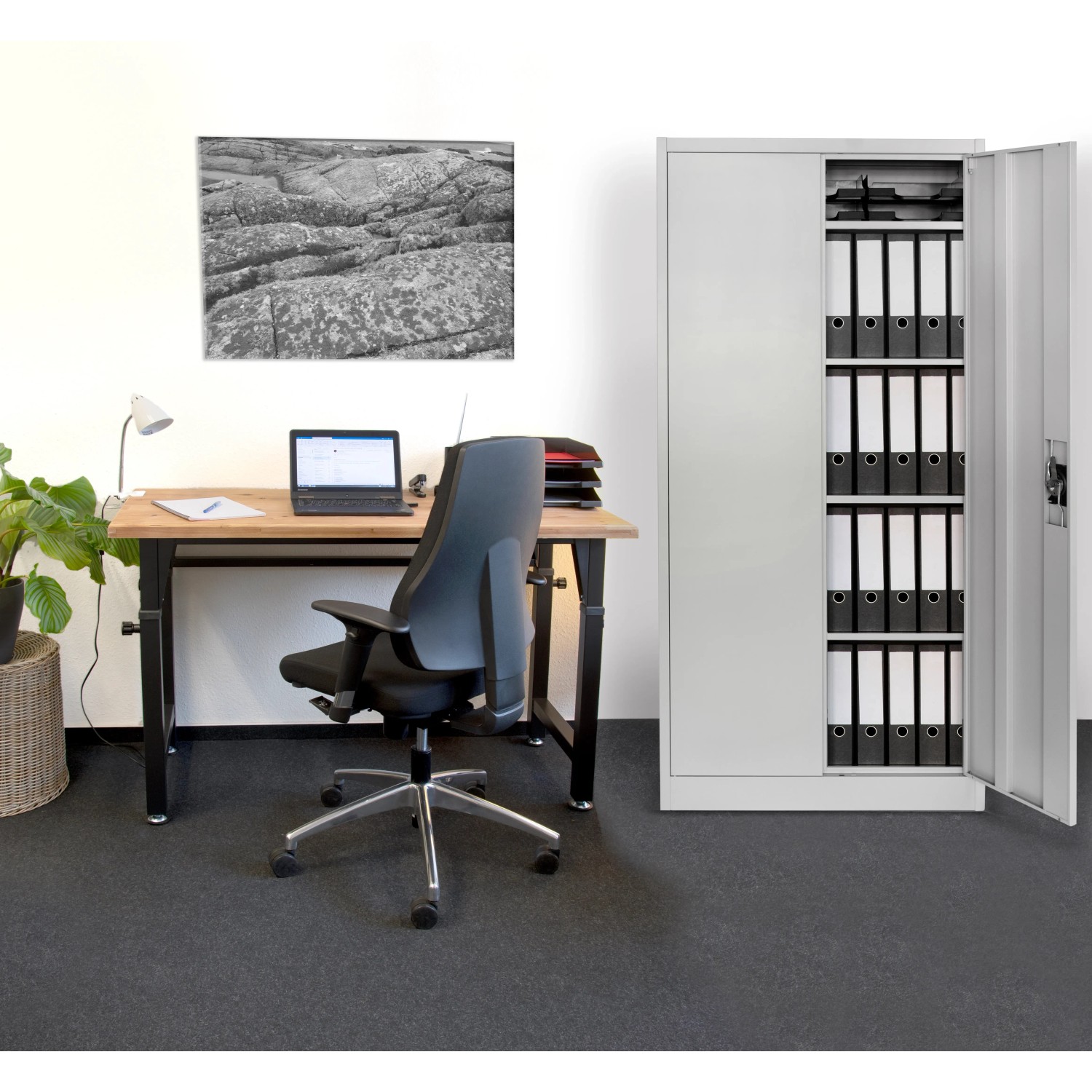 Foto eines lichtgrauen Rikta Metallschranks mit geöffneter Tür, gefüllt mit Aktenordnern im Büro.