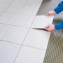 Fliesenleger verlegt Fliese mit Knauf Kleber- und Bodenelast Haftgrund.