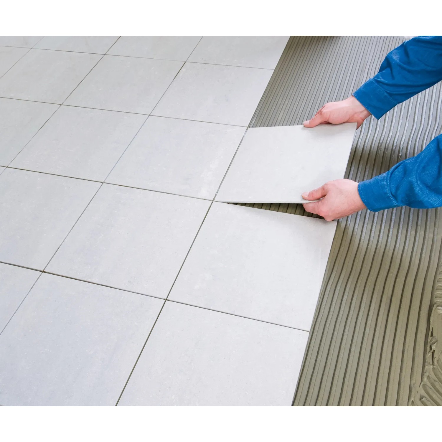 Fliesenleger verlegt Fliese mit Knauf Kleber- und Bodenelast Haftgrund.