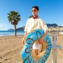 Bestway Schwimmring Donut, Ø 107 cm, blau mit bunten Streuseln, gehalten von Person am Strand.