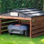 Dobar Mährobotergarage aus Holz, braun-schwarz, mit abnehmbarem Dach und Mähroboter im Garten.