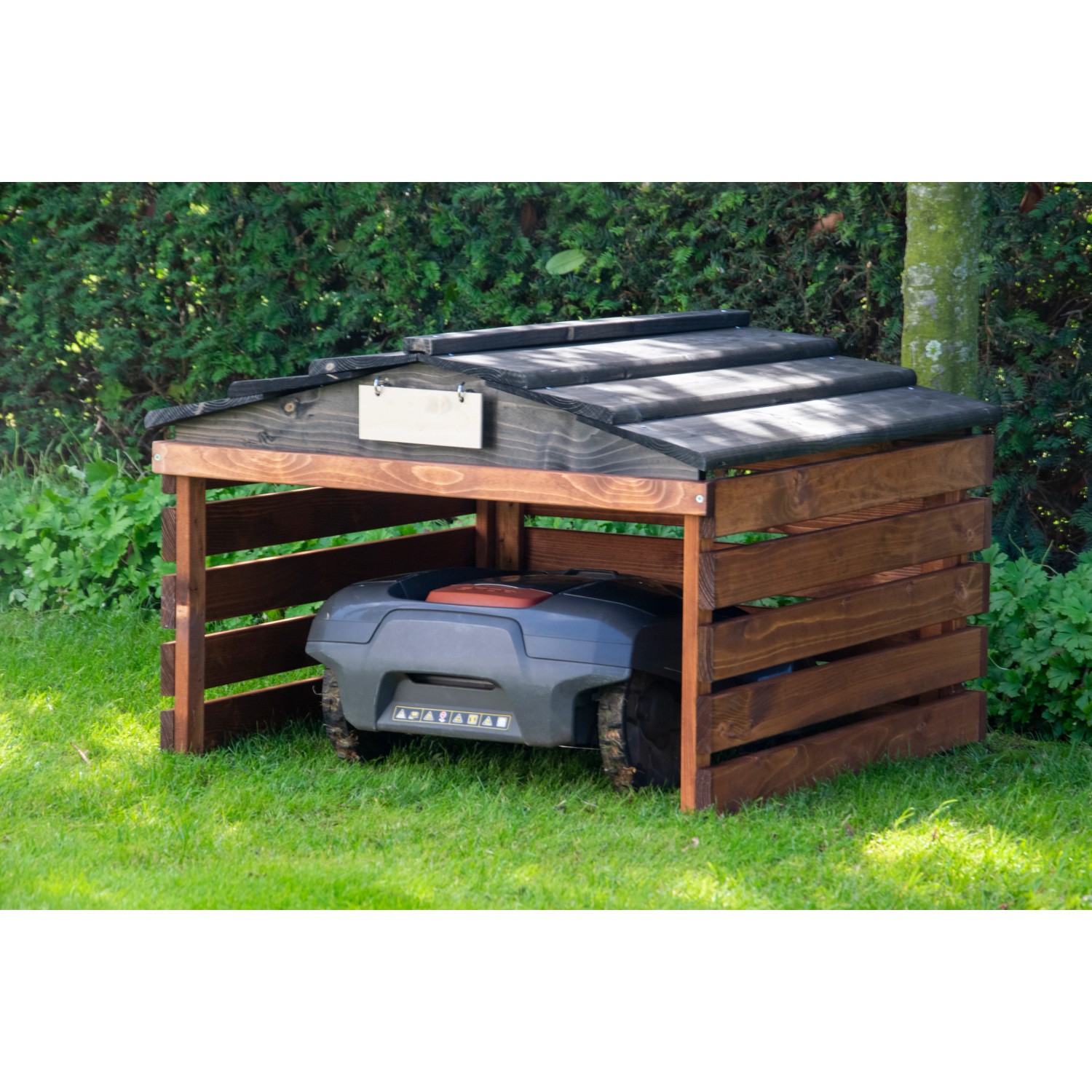 Dobar Mährobotergarage aus Holz, braun-schwarz, mit abnehmbarem Dach und Mähroboter im Garten.