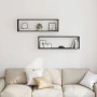 Zwei schwarze Würfelregale in Eichen-Optik an einer weißen Wand über einem Sofa dekoriert.