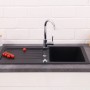 Schwarze Respekta Granitspüle Atlanta, 86x43,5 cm, mit Abtropffläche und Armatur auf einer Küchentheke.