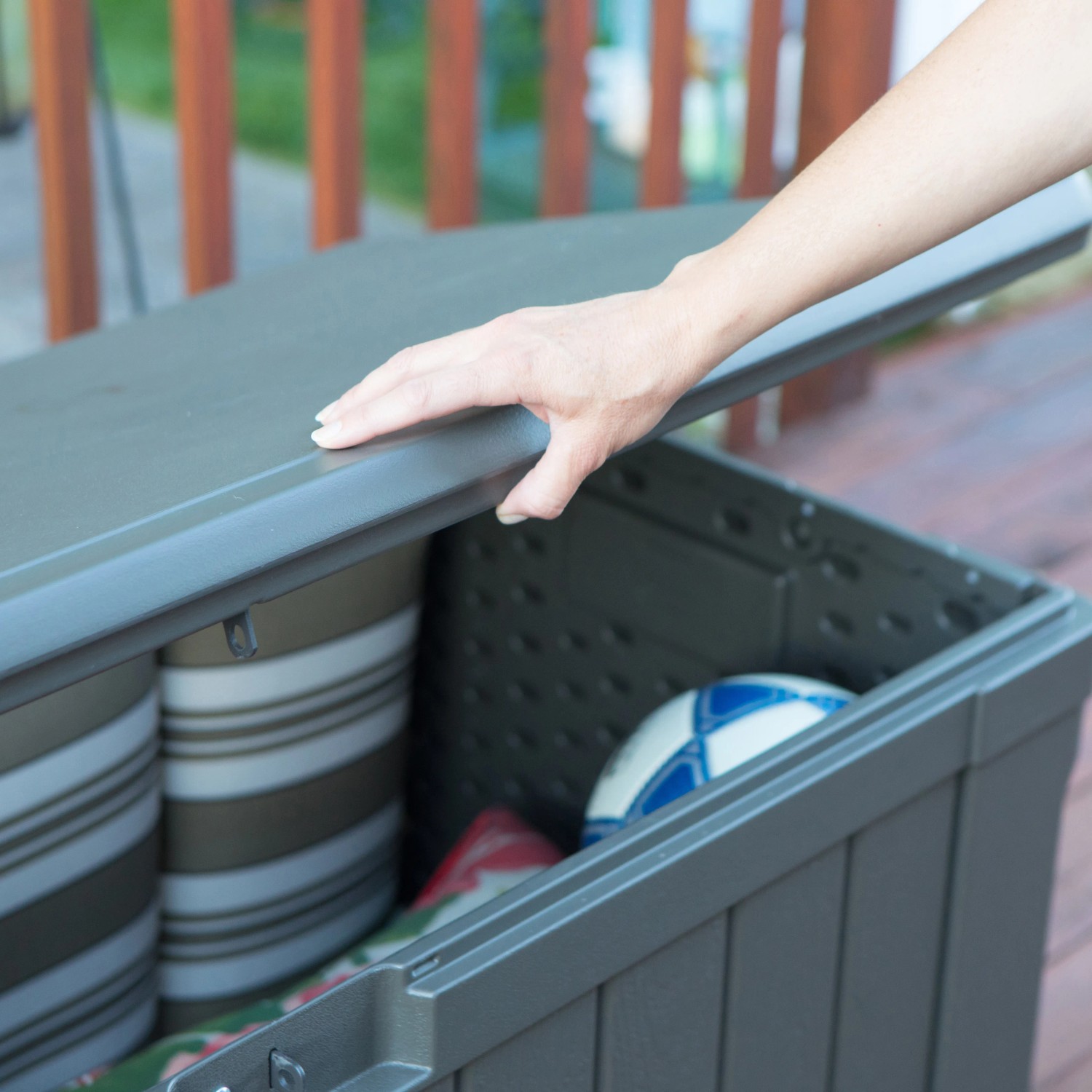Geöffnete, dunkelbraune Lifetime Gartenbox (128x64x67 cm) mit Kissen und Ball. Universalbox für Garten.