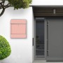 Silberner Banjado Design Briefkasten mit rosa Arabesque Motiv und Zeitungsfach an einer weißen Hauswand.