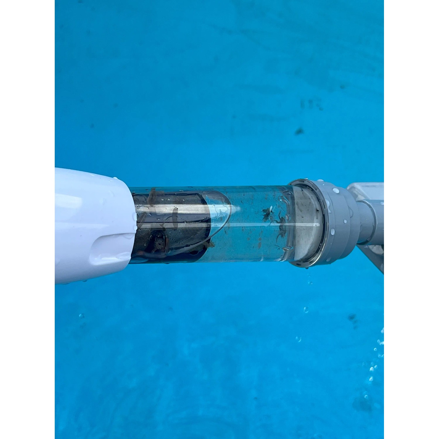 Pool-Handsauger im Einsatz: Weiß-grauer Poolsauger mit Akku unter Wasser.
