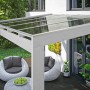 Weiße Skan Holz Terrassenüberdachung Novara mit klarer Doppelstegplatte und Sitzgruppe.