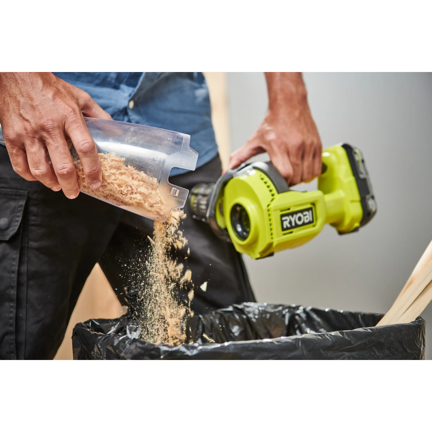 Ryobi Akku-Handsauger RHV18 beim Entleeren des Behälters in einen Müllsack.