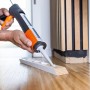 OBI Kartuschenpresse in Anwendung: Handwerker trägt Dichtmasse auf Holzleiste auf.