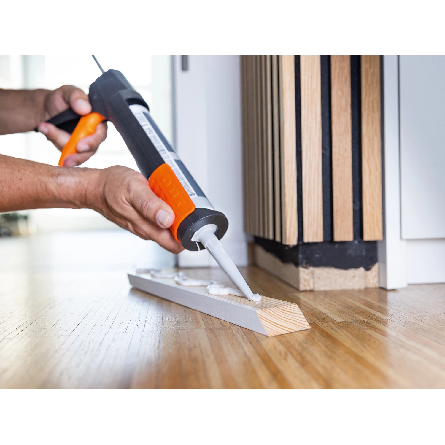 OBI Kartuschenpresse in Anwendung: Handwerker trägt Dichtmasse auf Holzleiste auf.