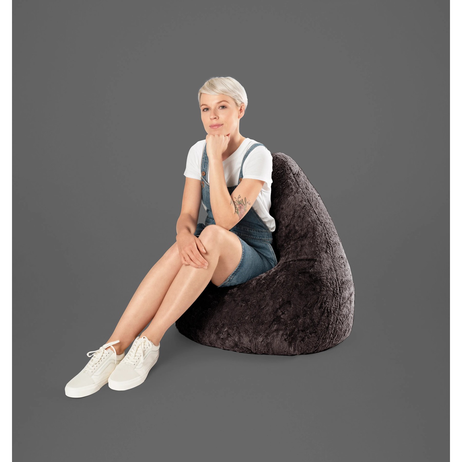 Frau sitzt im anthrazitfarbenen Sitting Point Sitzsack Fluffy 220 l. Bequemer Sessel für Wohnzimmer.