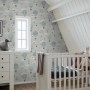 Dekorative Tapete mit blauen Luftballons und Wolken im Kinderzimmer. Weißes Babybett und Kommode.