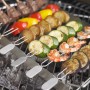 Rösle Grillspieße mit Halter, 6-teilig, bestückt mit Gemüse, Fleisch und Garnelen auf dem Grill.