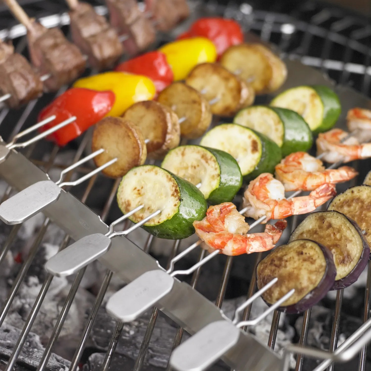 Rösle Grillspieße mit Halter, 6-teilig, bestückt mit Gemüse, Fleisch und Garnelen auf dem Grill.
